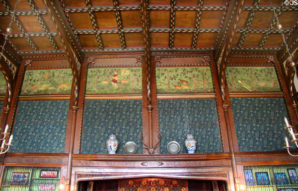 Green frieze of Orpheus playing his lyre & attracting wild animals (1893) by Charles Eamer Kempe over blue flowered wallpaper by Morris & Co in Great Parlor at Wightwick Manor. Wolverhampton, England.