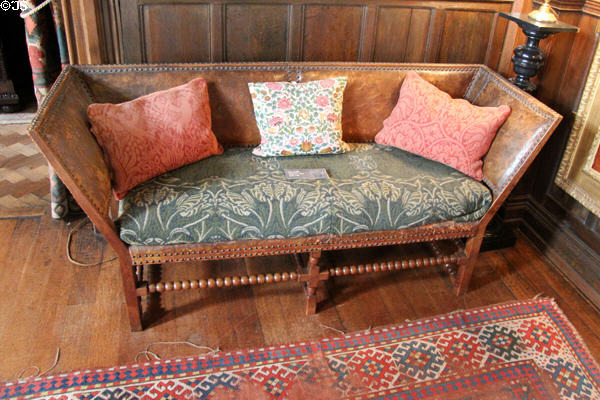 Oak settee in Cromwellian style with seat covered by Morris-style fabric & pillows (1890s) by Charles Eamer Kempe in Great Parlor at Wightwick Manor. Wolverhampton, England.