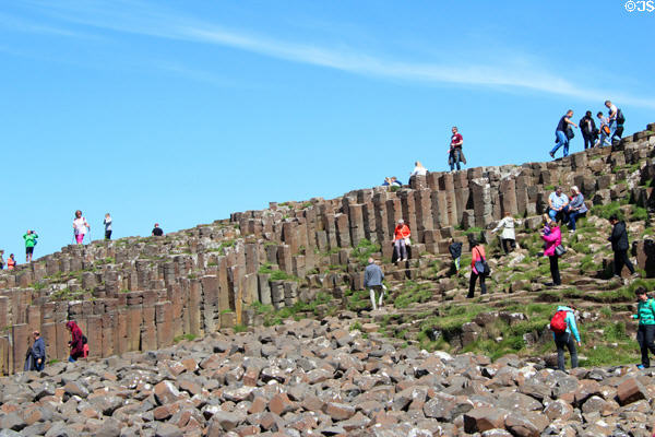 Visitors climb the hexagonal blocks of Giant's Causeway. Northern Ireland.