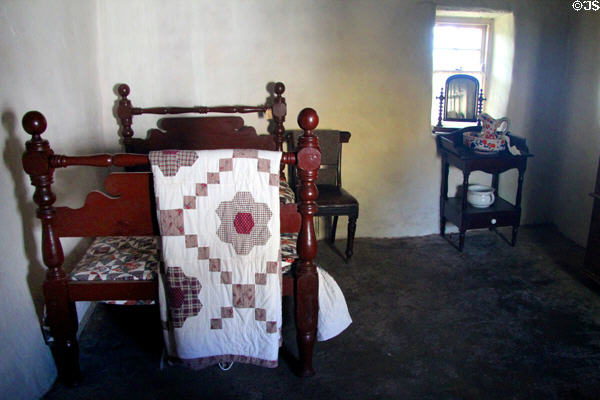 Bed with coverlet & wash stand in Mellon Homestead at Ulster American Folk Park. Omagh, Northern Ireland.