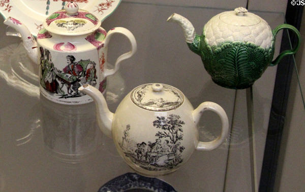 Creamware teapots from Staffordshire: transfer print fortune teller (1778-82) by William Greatbatch; transfer print tea party (1770) by Derby Pot Work; & cauliflower (c1765) at British Museum. London, United Kingdom.