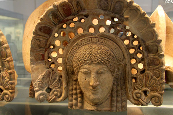 Etruscan-Latin painted terracotta antefix molded with head of woman in elaborate frame (520-470 BCE) from Lanuvium, Latium at British Museum. London, United Kingdom.