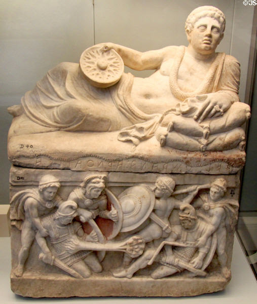 Etruscan carved alabaster cinerary urn with reclining man on lid & battle panel on chest (200-100 BCE) from Chiusi at British Museum. London, United Kingdom.