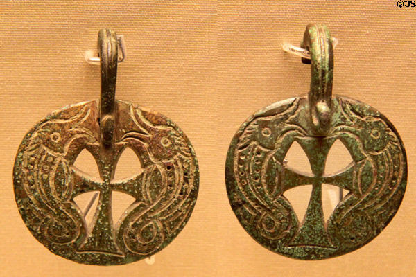 Christianized Celtic bronze bowl mounts with dolphins framing a cross (6th-7thC) from Faversham, Kent at British Museum. London, United Kingdom.