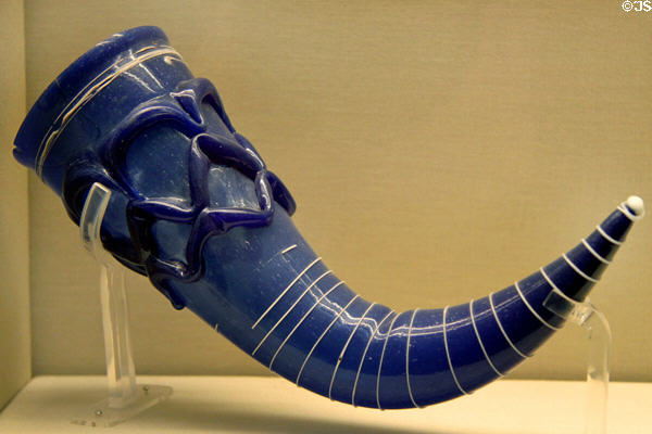 Blue glass drinking-horn with applied lattice work around neck & white trailing around body (late 6thC) from Lombardy at British Museum. London, United Kingdom.