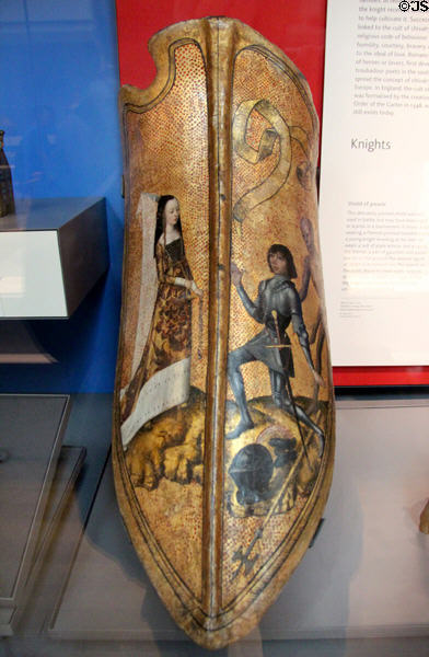 Parade shield showing lady with Flemish pointed headdress with knight kneeling at her feet (c1475-1500) from Flanders or Burgundy, France at British Museum. London, United Kingdom.