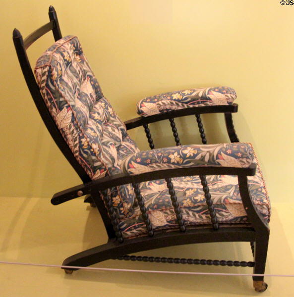 Armchair with back adjustable to recline to several angles which became widely copied with generic name Morris Chair (c1866) by Philip Webb for Morris & Co (reupholstery 1970 has nothing to do with Morris) at Morris Gallery. London, United Kingdom.
