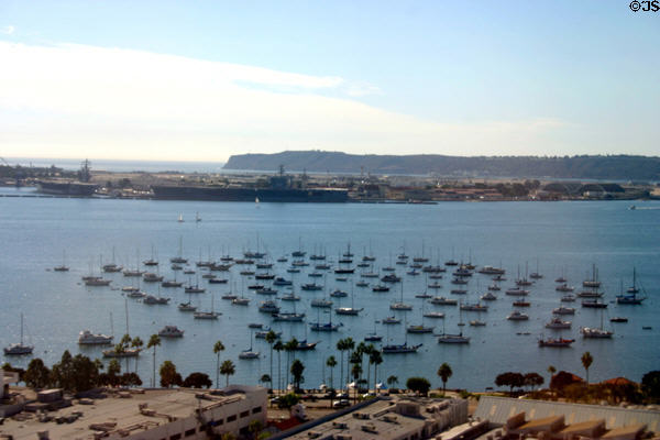 Pleasure craft in harbor with aircraft carriers in distance from air. San Diego, CA.