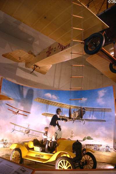 Barnstormers wing walker about to climb ladder to Standard from replica of 1922 Ford Speedster T at San Diego Aerospace Museum. San Diego, CA.