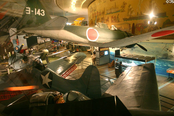 World War II aircraft seen against March of Transportation Mural by Juan Larrinaga at San Diego Aerospace Museum. San Diego, CA.