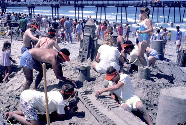 Sculptors shaping sand castle at sand sculpting contest on Coronado Island beach. San Diego, CA.
