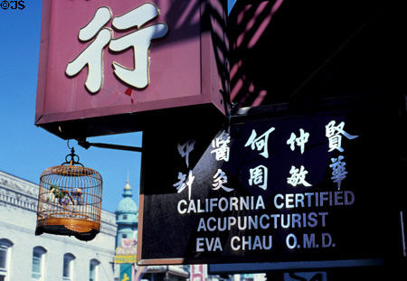 Bird cage hangs from sign in Chinatown. San Francisco, CA.