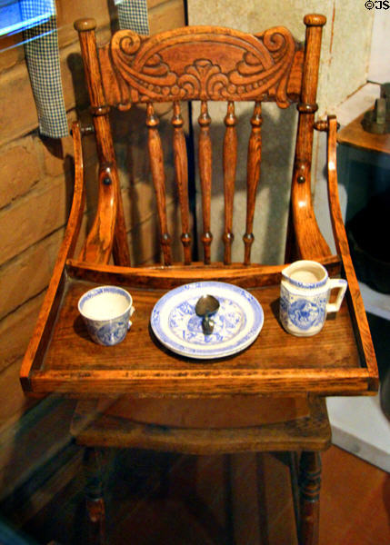 Antique wooden high chair with child's dishes at Mariposa Museum. Mariposa, CA.