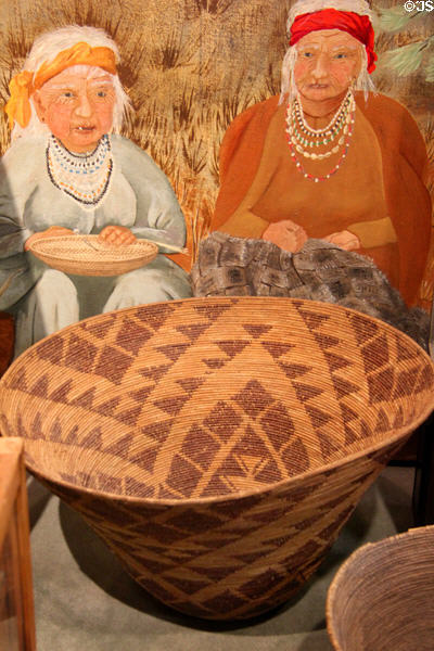Native American basket with depiction of Native American women basket making in the background at El Dorado County Historical Museum. Placerville, CA.