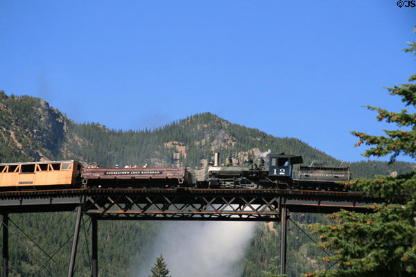 Georgetown Loop Railroad steam locomotive #12 crosses loop bridge against mountain backdrop. Georgetown, CO.