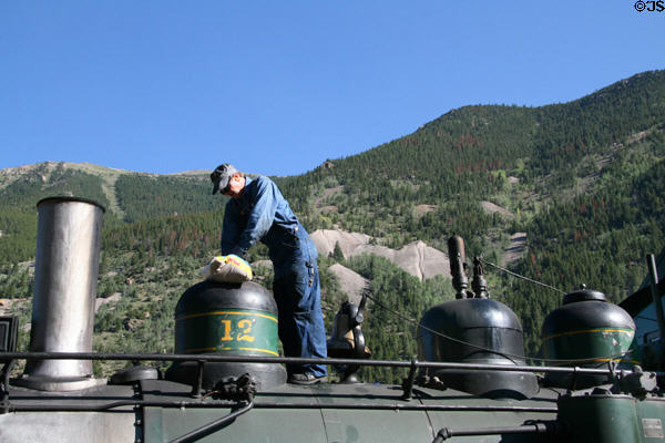 Adding sand to bell atop Georgetown Loop Railroad steam locomotive to allow Engineer to eject sand between wheels & track for traction on mountain grades. Silver Plume, CO.