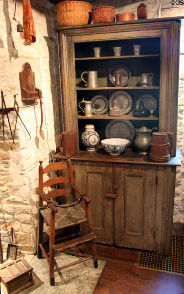 Cupboard with pewter, ceramics behind high chair at Henry Whitfield State Museum. Guilford, CT.
