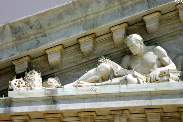 Man reading books beside symbols of authority on Supreme Court pediment. Washington, DC.