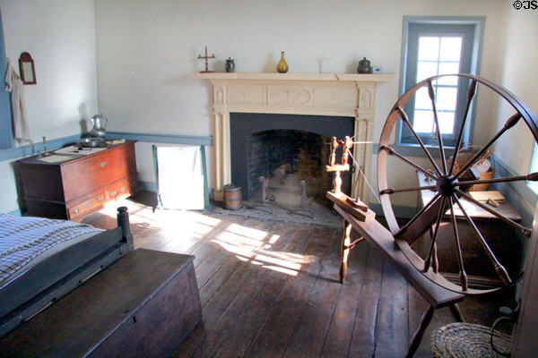 Large bedroom with fireplace & spinning wheel at Old Stone House. Washington, DC.