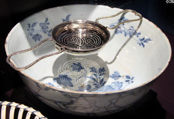 Earthenware punch bowl (1760-80) from Lambeth, England & silver punch strainer (1778-9) by John Scofield of London, England at DAR Memorial Continental Hall Museum. Washington, DC.