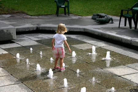 Little girl plays in fountain among Alligator statues. Orlando, FL.