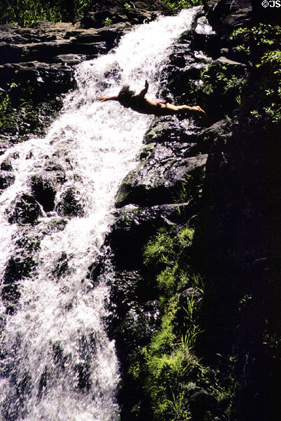 Diving from rocky cliff at Waimea Valley Adventure Park. Oahu, HI.