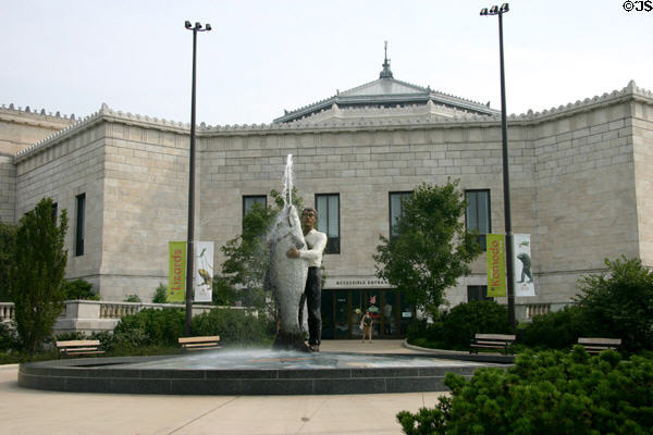 Man with fish statue at an entrance of Shedd Aquarium. Chicago, IL.
