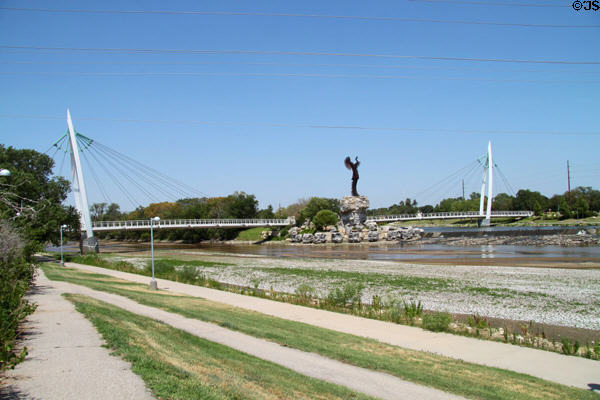 Keeper of the Plains sculpture at confluence of Arkansas & Little Arkansas Rivers framed by pedestrian suspension bridge. Wichita, KS.