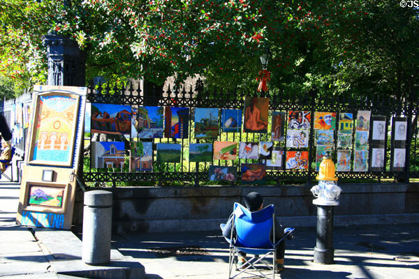 Artist displays paintings on cast iron fence of Jackson Square. New Orleans, LA.