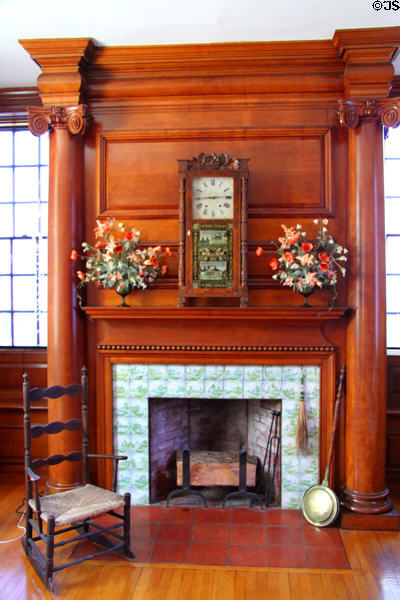 Wood paneled fireplace with mantle clock & flowers at Mayflower Society House. Plymouth, MA.