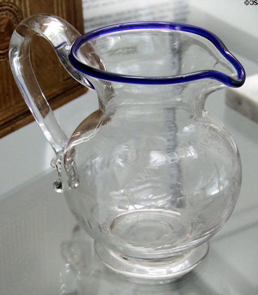 Blown & engraved clear glass pitcher with blue rim (c1840-50s) at Sandwich Glass Museum. Sandwich, MA.