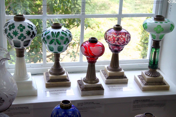 Collection of colored cut double overlay glass lamps (c1855-80) by Boston & Sandwich Glass Co. at Sandwich Glass Museum. Sandwich, MA.