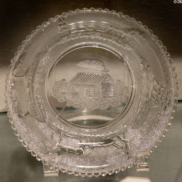 Pressed glass plate with log cabin, sailing ship & factory by New England Glass Co. at Corning Museum of Glass. Corning, NY.