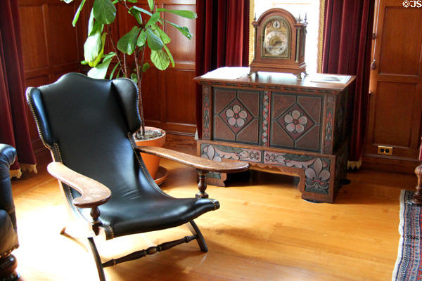 Reclining wing back armchair beside elaborate cabinet in billiard room at Eastman House. Rochester, NY.