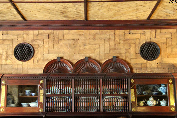 Cork-tile ceiling & wall, spool-work roundels over built in walnut buffet with spindle screen (1881) by Stanford White in Dining Room at Kingscote. Newport, RI.