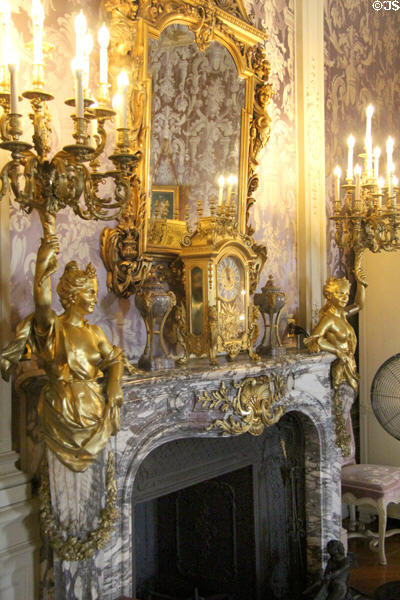 Fireplace with sculptures holding torcheres & mantle clock under mirror in Mrs. Vanderbilt's bedroom at Marble House. Newport, RI.
