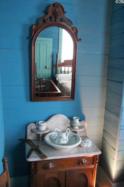 Bedroom washstand with basin & pitcher under mirror in Yates House at Sam Houston Park. Houston, TX.