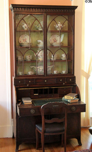 Rolltop desk with bookcase displaying porcelain in parlor at Neill-Cochran House Museum. Austin, TX.