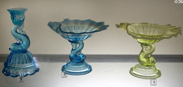 Colored pressed glass candlestick & compots supported by dolphins (1860-80) prob. from Pittsburgh, PA at Bennington Museum. Bennington, VT.