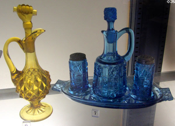 Yellow pressed glass cruet with fist stopper (1880-1900) from Pittsburgh, PA & blue pressed glass cruet set (1890-1900) by Bellaire Goblet Co. of Bellaire, OH at Bennington Museum. Bennington, VT.