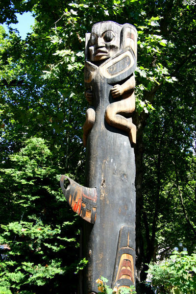 Man riding tail of a whale totem pole (1980s) by Duane Pasco in Occidental Park. Seattle, WA.