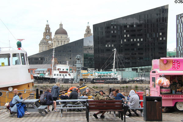 Historic ships before Merseyside Maritime Museum, black angular buildings of Mann Island Discover center & towers of Three Graces. Liverpool, England.