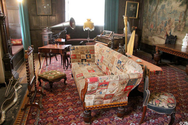 Music room with patchwork covered sofa & fire screen with wood spooled frame at St Fagans Castle. Cardiff, Wales.