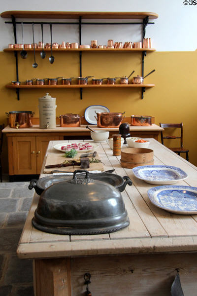 Work table & shelves displaying rows of copper pans & jelly molds in kitchen at St Fagans Castle. Cardiff, Wales.