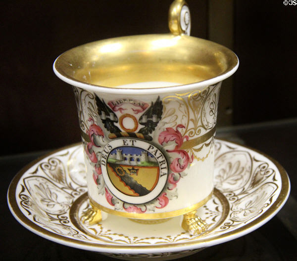 Soft--paste porcelain cabinet cup & saucer (1818-20) with Latin "God & Country" emblem, made in Nantgarw, Wales & possibly decorated by Chamberlain of Worcester at National Museum of Wales. Cardiff, Wales.