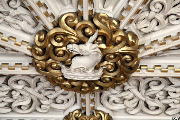 Detail of gilded medallion with sculpted plaster figure on ornate ceiling in Library at Penrhyn Castle. Bangor, Wales.
