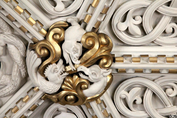 Detail of gilded medallion with intertwined sculpted plaster figures on ornate ceiling in Library at Penrhyn Castle. Bangor, Wales.