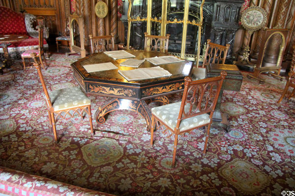 Light side chairs for ladies around inlaid octagonal table on floral patterned rug in Drawing Room at Penrhyn Castle. Bangor, Wales.