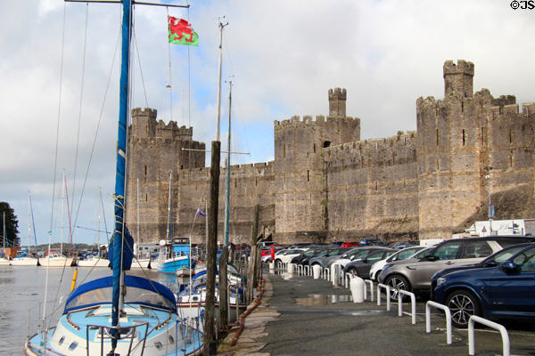Caernarfon Castle (late 13thC), built by Edward) towering over the port on the banks of the River Seiont. Caernarfon, Wales.