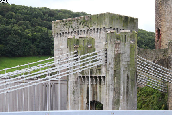 Supporting chains of Telford suspension bridge with tower of Conwy Castle to which they are anchored in background. Conwy, Wales.